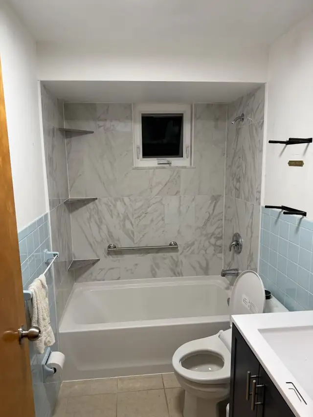 Marble-look tub surround with corner shelves, a grab bar and a window