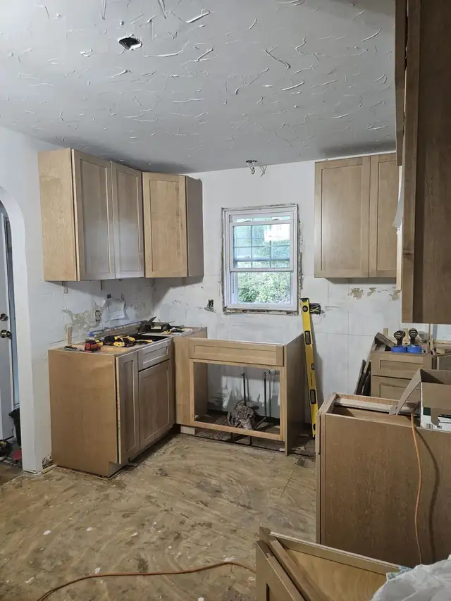 Maple shaker kitchen cabinets being hung by Russell in an older home in Akron, Ohio